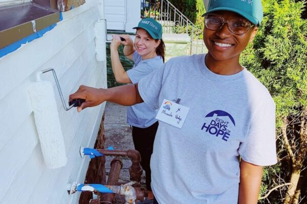 Volunteers painting house exterior on the East Side