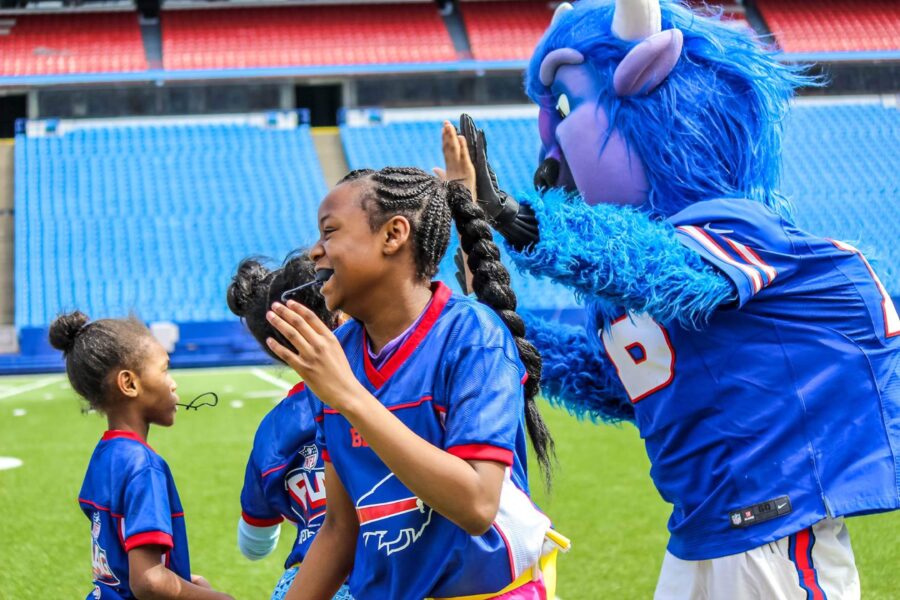 Students playing flag football at New Era Field meeting Billy Buffalo