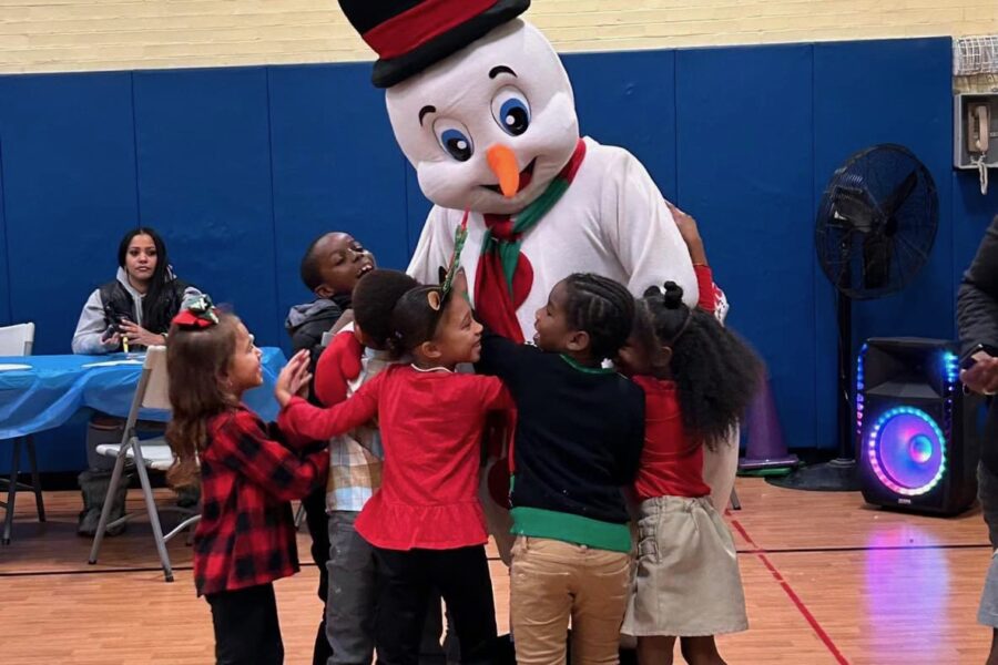 Frosty the Snowman meeting students in school gym with a big group hug